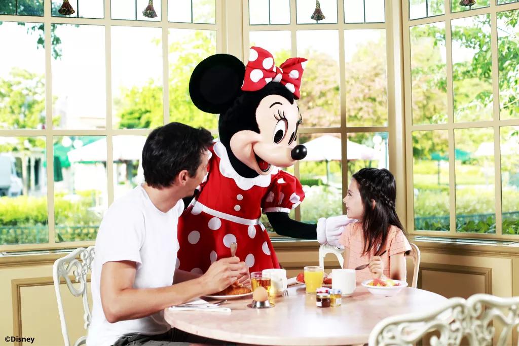 Plaza Gardens Breakfast at Disneyland Paris Minnie Mouse with two guests eating breakfast at Plaza Gardens Restaurant