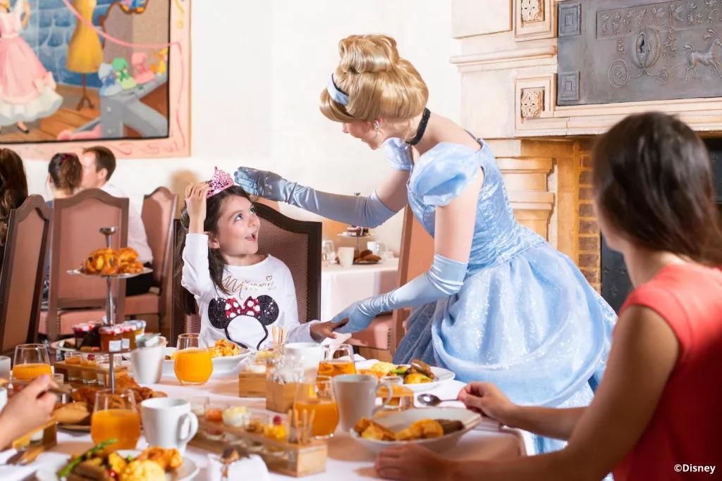 Cinderella at Auberge de Cendrillon Cinderella talking to a young girl sat at a table at Auberge de Cendrillon