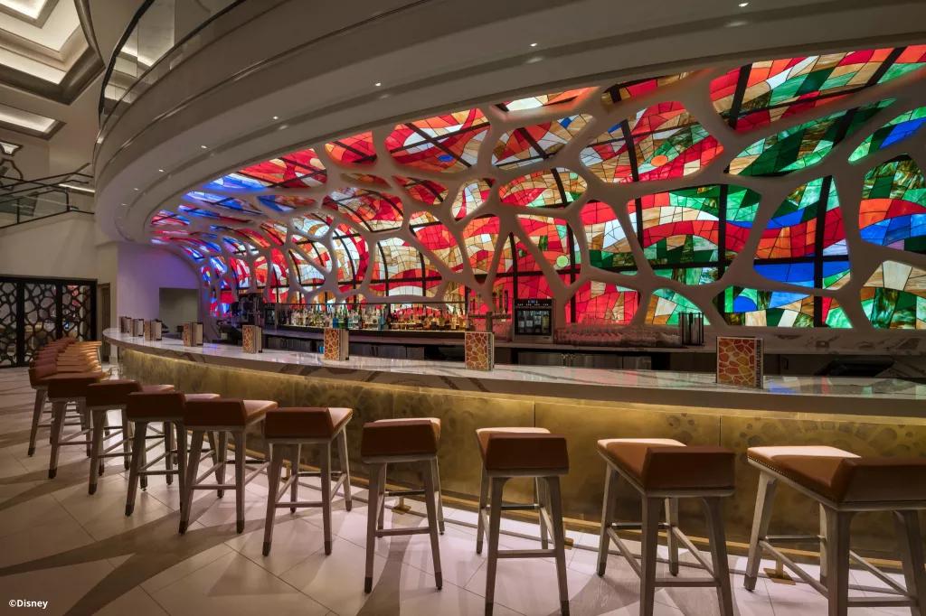 The Barcelona Lounge at Disney's Coronado Springs Resort A row of bar stools in front of a bar with a bright colourful stained glass window backdrop