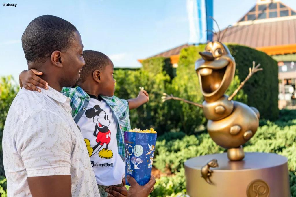 Olaf Golden Statue A man holding his son pointing towards the golden Olaf statue in EPCOT