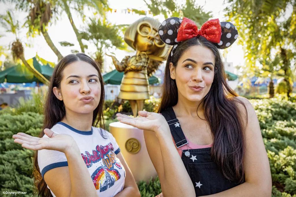 Edna Mode Golden Statue Two female guests posing with their hands raised in front of the Edna Mode golden statue