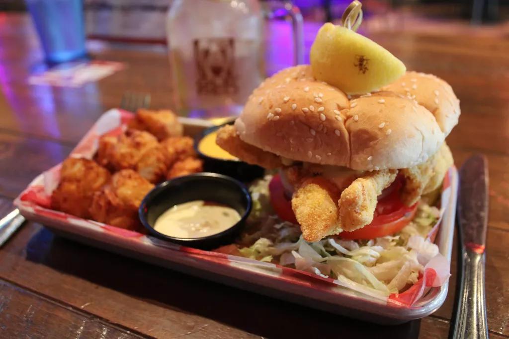 Grouper Sandwich at Ole Red A fried fish sandwich served with pickles and tater tots