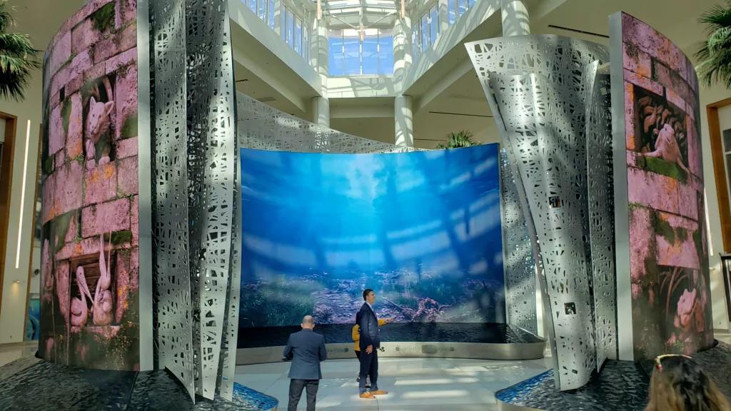 The Moment Vault at Terminal C Two men standing within three large curved screens showing videos of underwater