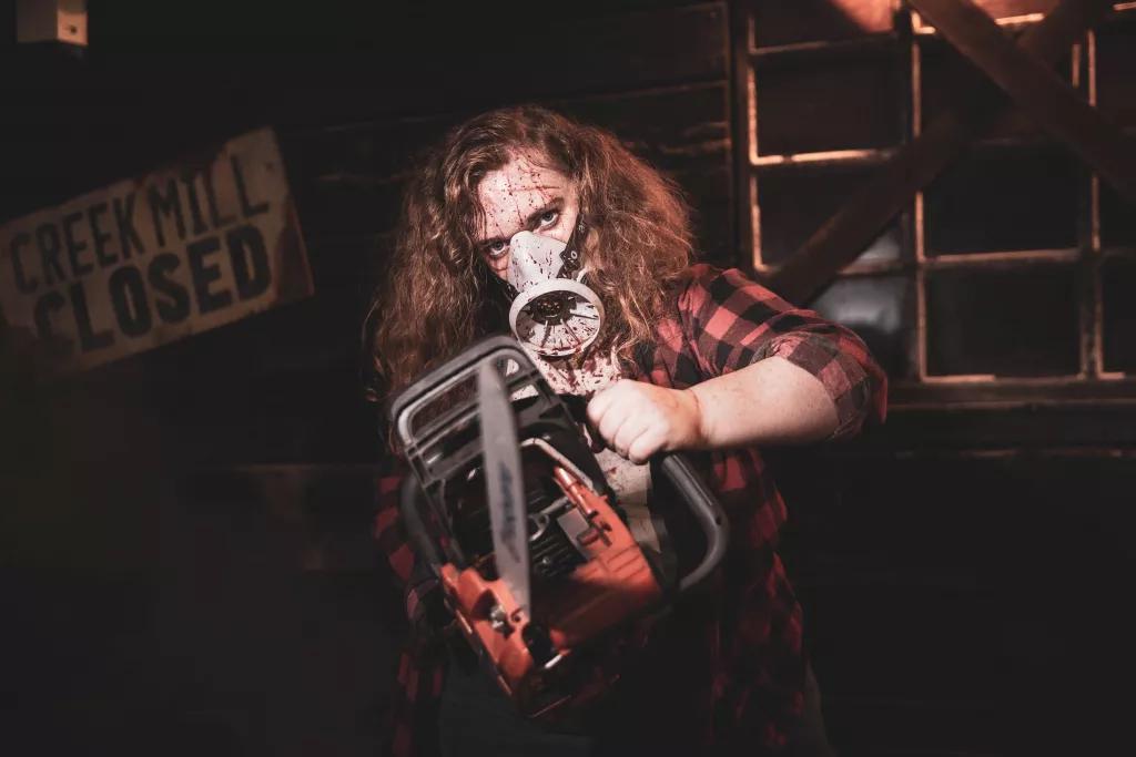 Creek Freak Massacre A man in a checked shirt and wearing a gas mask splattered with blood and holding a chainsaw