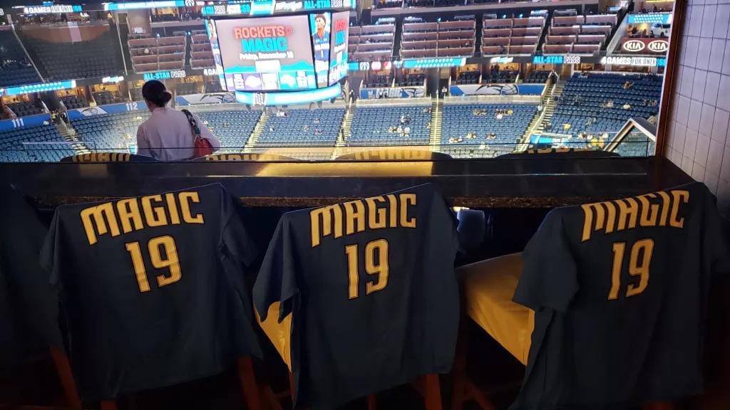 Orlando Magic Tshirts 3 Orlando Magic tops hung on the back of bar stools with a view of the basketball court