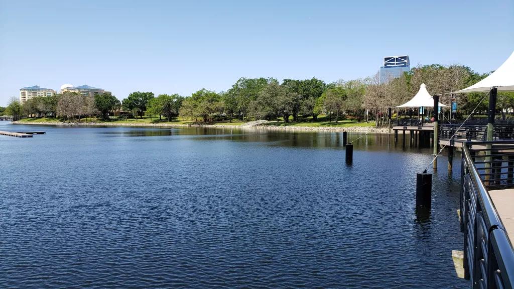 Altamonte Springs A calm lake in front of a grassy bank lined with trees and a clear blue sky