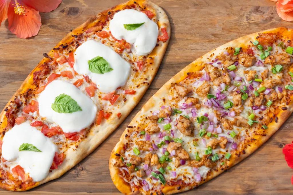 Pizzas at Hibiscus Hideaway Two thin crust pizzas on a wooden board surrounded by flowers