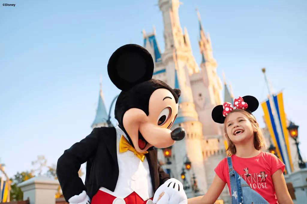 Mickey Mouse at Walt Disney World Mickey Mouse holding hands with a young girl in front of Cinderella Castle