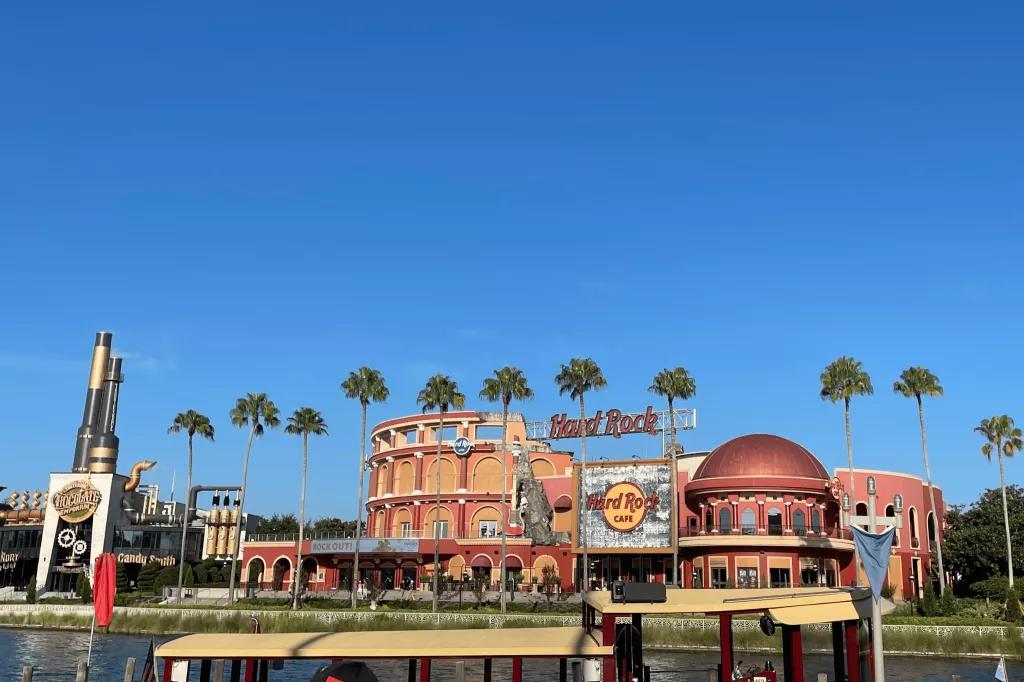 Hard Rock Cafe at Universal Orlando The exterior of the Hard Rock Cafe seen across a waterway, behind a row of palm trees