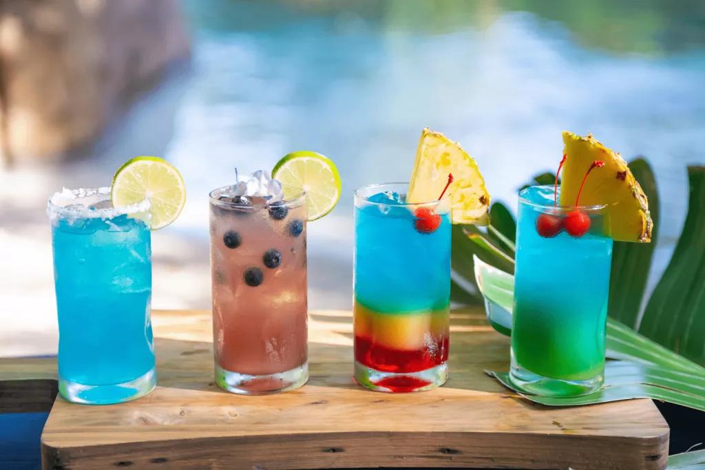 Blue Bamboo Bar Cocktails Four colourful cocktails on a wooden board in front of a sandy beach