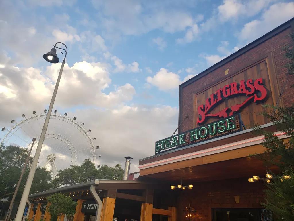 Saltgrass Steakhouse The outside of Saltgrass Steakhouse clad with wood panels, with The Wheel in the background