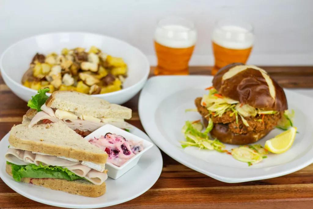 Taste of Space: Fall Bites A sandwich, filled pretzel roll and potato casserole on a table with two glasses of beer