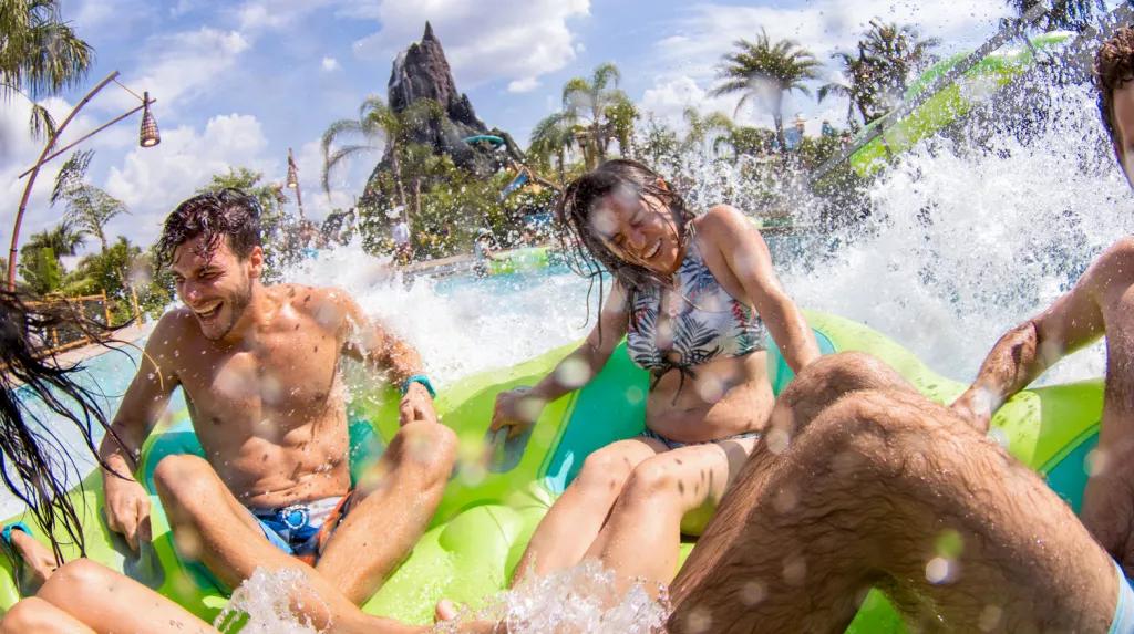Volcano Bay Water Theme Park Guests in a rubber raft getting splashed in front of the volcano at Volcano Bay