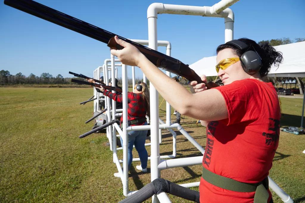 Clay Pigeon Shooting A woman in a red tshirt at the front of a line of people pointing guns for clay pigeon shooting