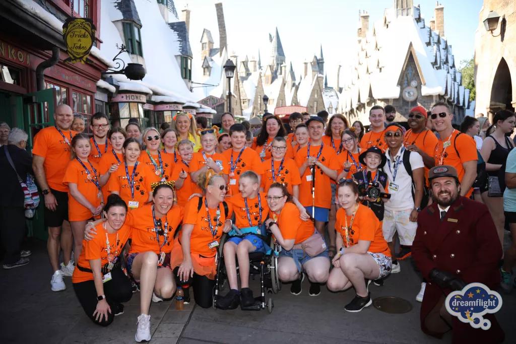 Dreamflight 2022 at Universal Orlando A large group of children and adults wearing bright orange tshirts standing in the Wizarding World of Harry Potter