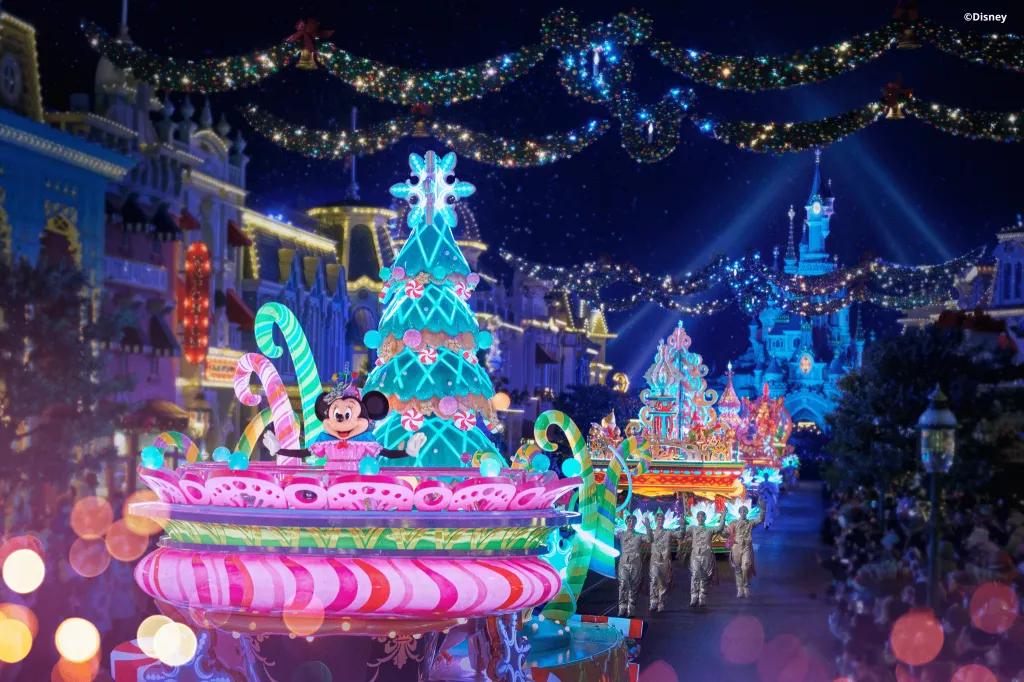Mickey's Dazzling Christmas Parade Christmas parade floats lit up with neon lights carrying Disney characters including Minnie Mouse. Sleeping Beauty Castle is in the background
