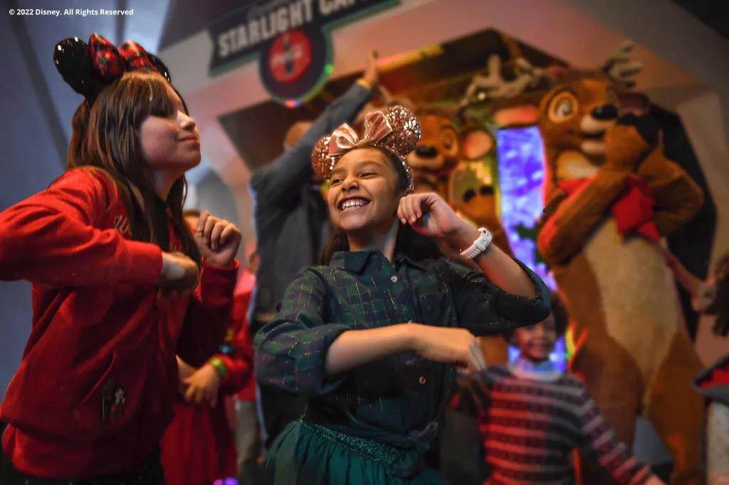 Club Tinsel at Cosmic Ray's Starlight Cafe Two young girls wearing Minnie ears dancing with two reindeer in the background