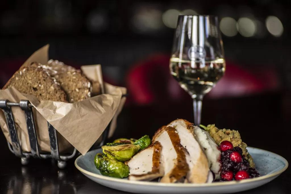Thanksgiving at Raglan Road A plate of sliced turkey, stuffing and cranberry sauce, next to a glass of wine and a basket of bread