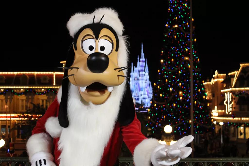 Christmas at Walt Disney World Goofy dressed as Santa Claus with a lit up Cinderella Castle in the background