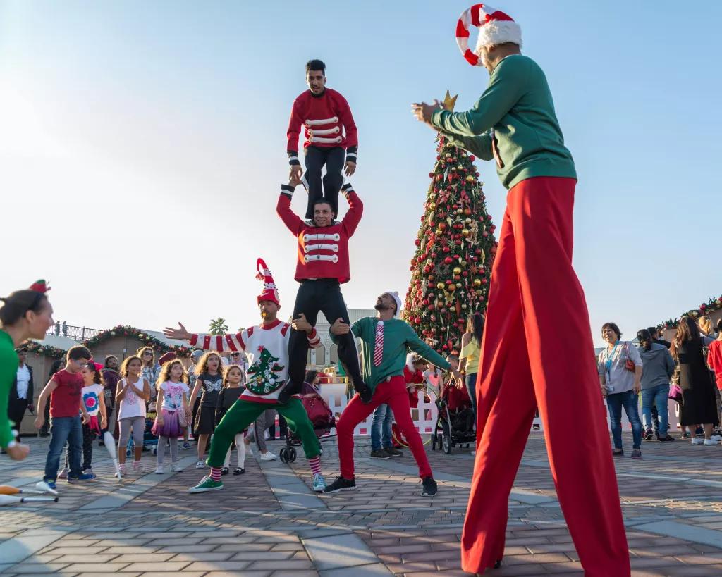 Christmas at Riverland Dubai Acrobatic performers dressed like elves, performing stunts and walking on stilts