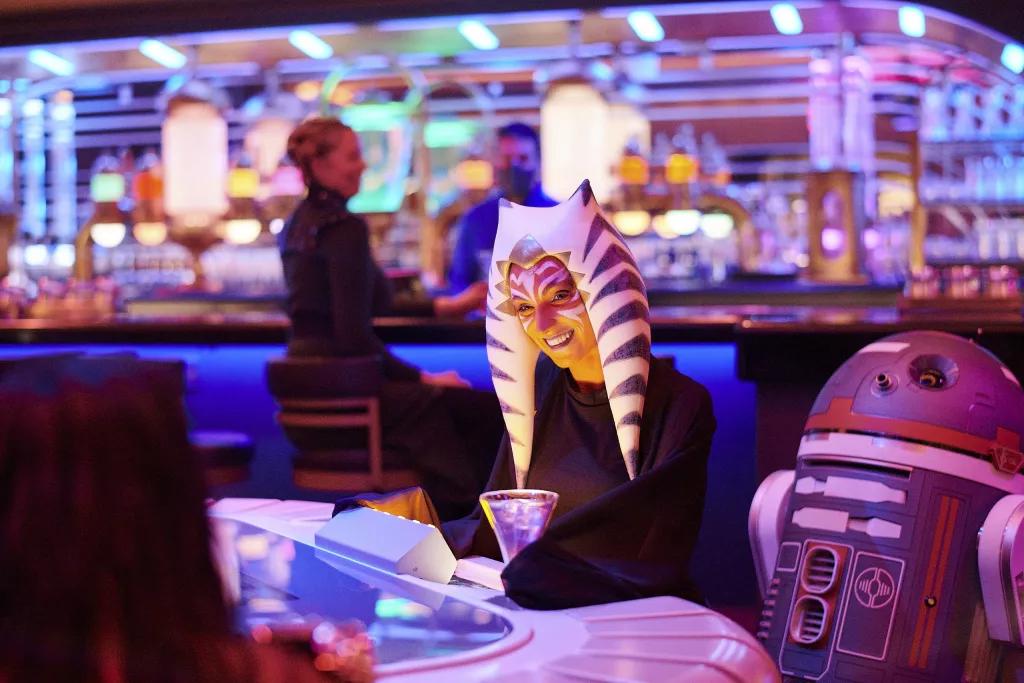 Star Wars Galactic Starcruiser at Walt Disney World A Togruta Star Wars character drinking a cocktail next to a droid on the Galactic StarCruiser
