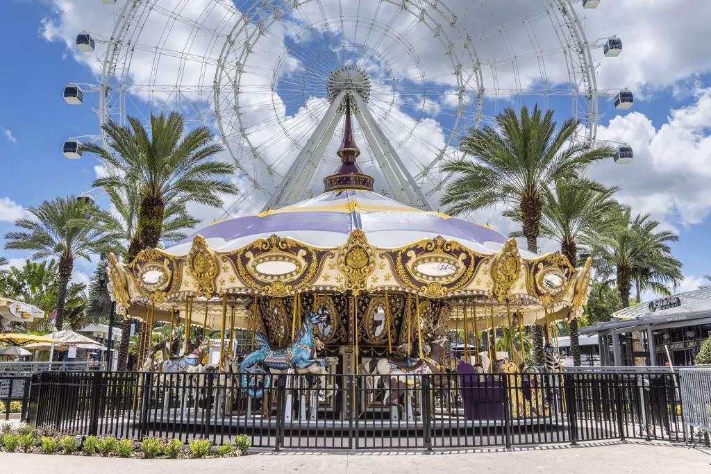 ICON Park A golden carousel with multi-coloured horses in front of a large observation wheel