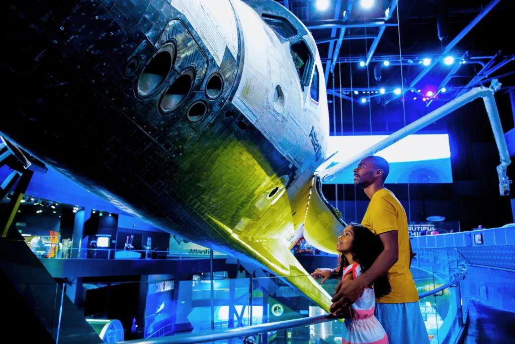 Space Shuttle Atlantis A father with his arm around his young daughter looking up at the Space Shuttle Atlantis