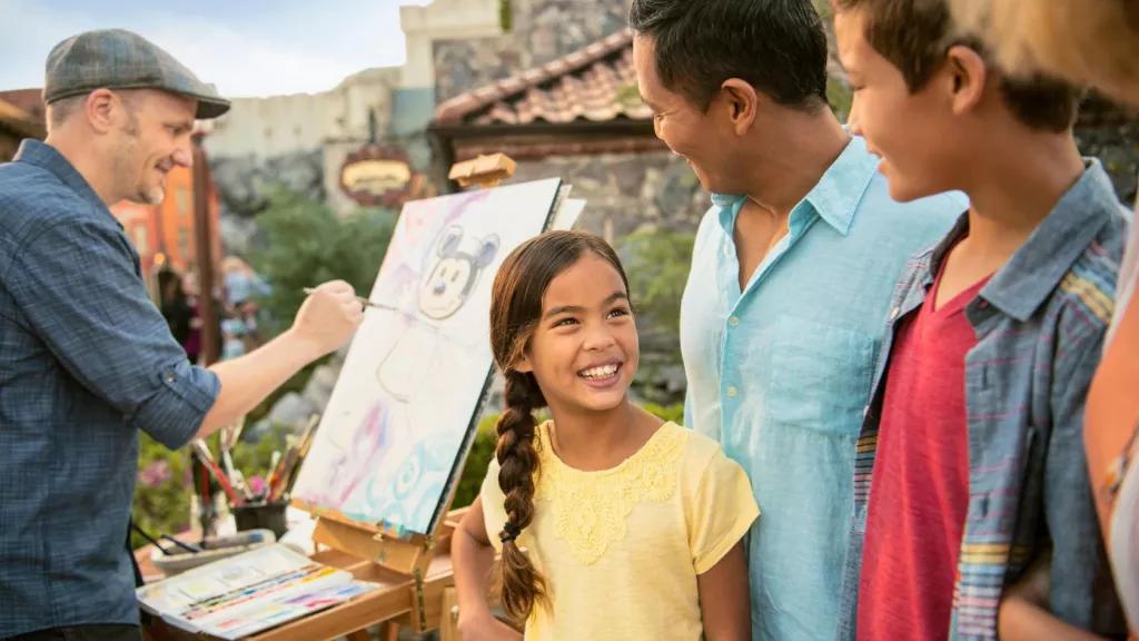 Artists at EPCOT's Festival of the Arts A family watching a man paint a picture of Mickey Mouse on an easel