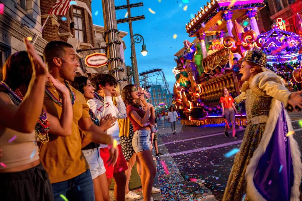 Mythical Realms of Mardi Gras Parade A group of people clapping for a parade performer in an elaborate outfit in front of a large parade float