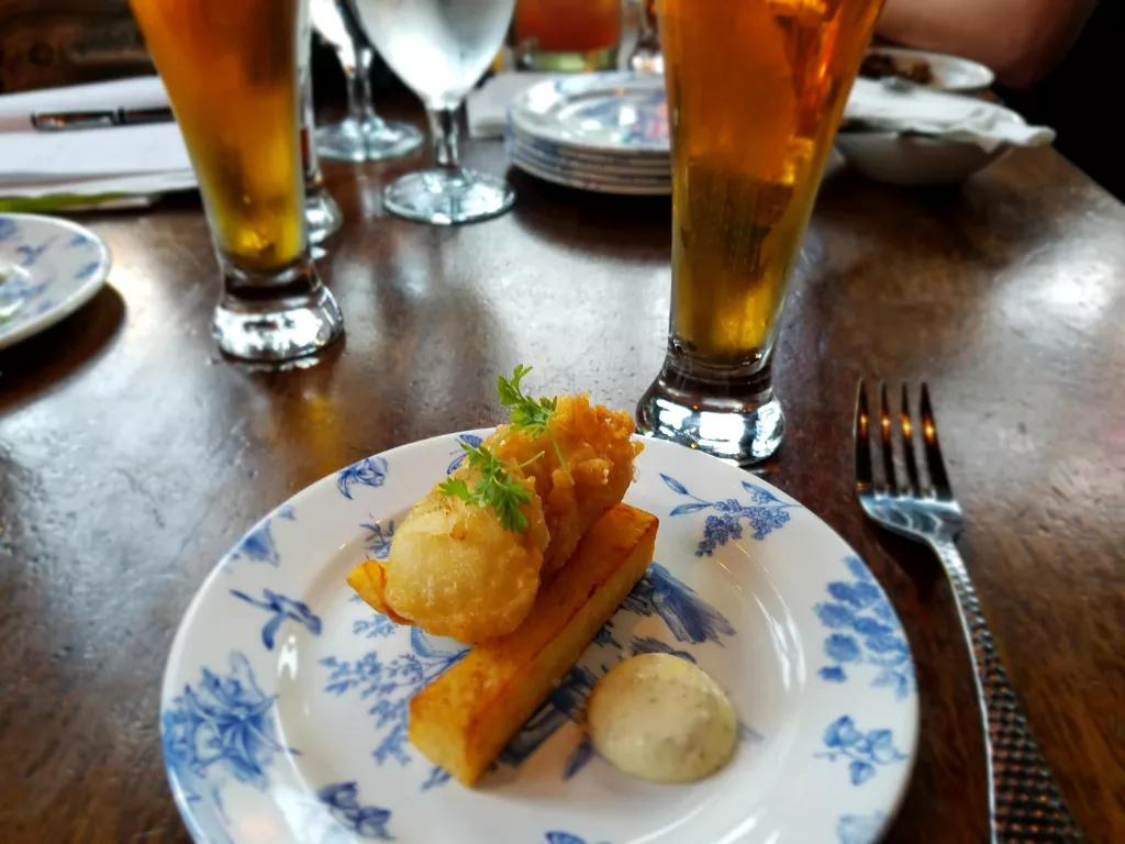 Fish and Chips at Raglan Road A plate of fish and chips on a table next to two pints of beer