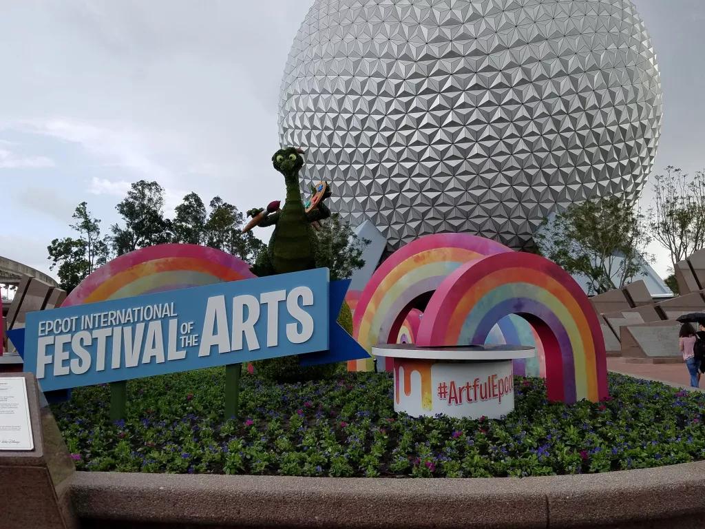EPCOT Festival of the Arts A topiary of Figment the dragon in front of Spaceship Earth with a Festival of the Arts sign