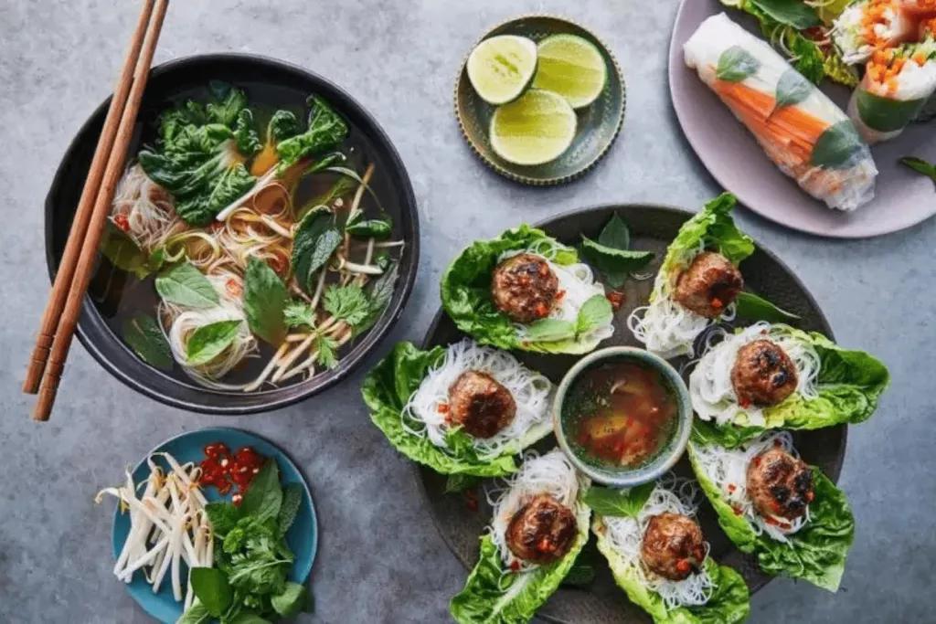 Jamie Oliver Cooking School Multiple plates of Vietnamese food like spring rolls, noodle soup and lettuce wraps