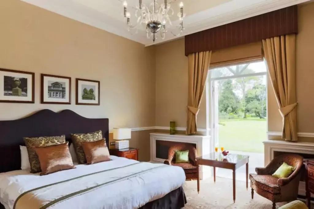 One Night Classic Break A hotel room with a bed and two armchairs with open French doors looking out to a grassy garden