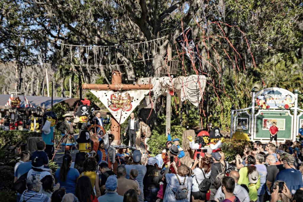 Opening of Pirate River Quest A large crowd of people looking towards people on a raised stage while confetti is falling on them