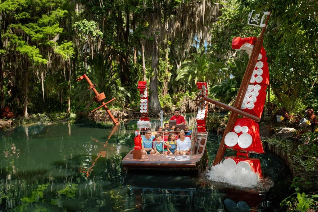 Pirate River Quest at Legoland Florida A boat designed to look like Lego going through water in a jungle-like setting, with a Lego octopus coming out of the water
