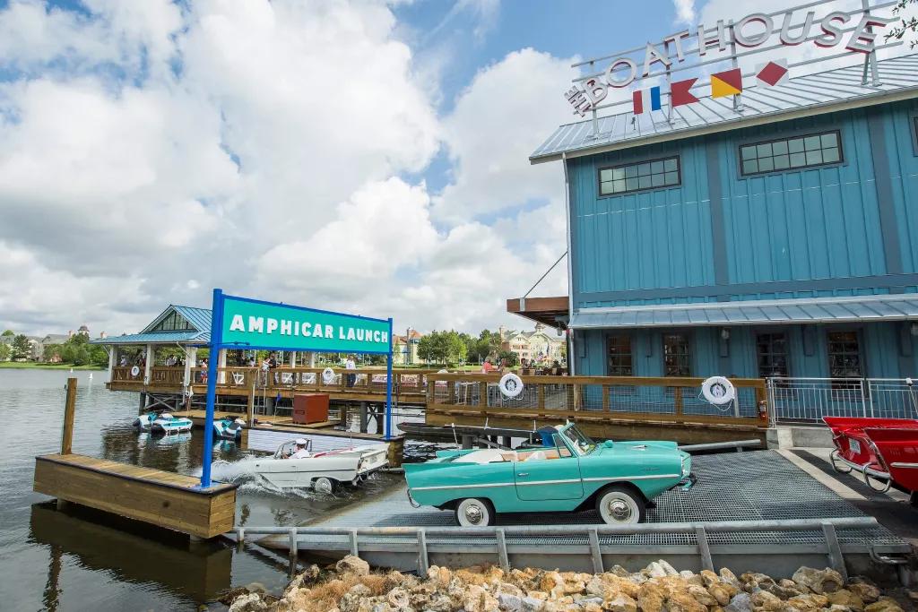 The Boathouse at Disney Springs Amphicars on a ramp leading into a lake in front of a blue panelled building with a sign reading Boathouse