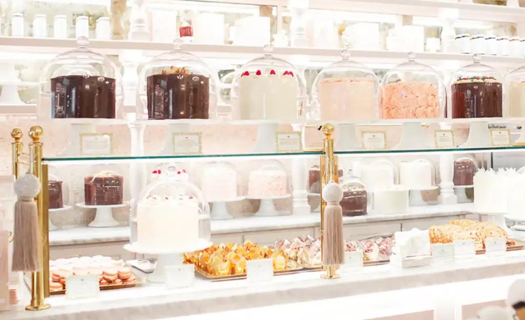 The Cake Bake Shop A glass display cabinet full of layer cakes and individual pastries