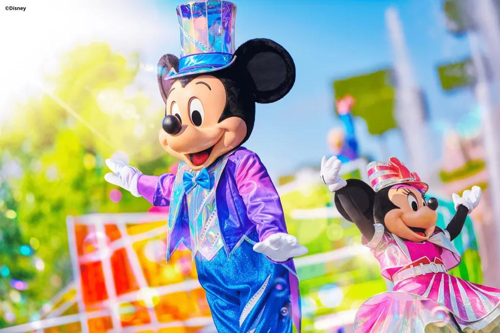 Dream... and Shine Brighter Mickey and Minnie Mouse in bright coloured iridescent clothes in front of a parade float