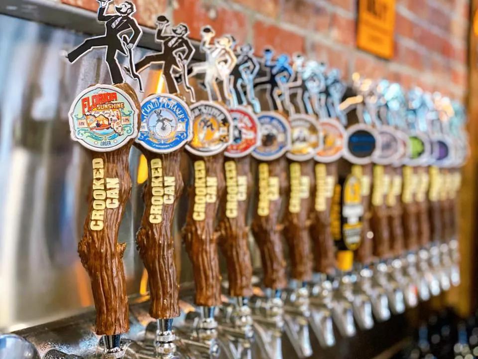 Crooked Can Brewery A line of beer taps designed to look like tree branches, labelled with "Crooked Can" in gold lettering