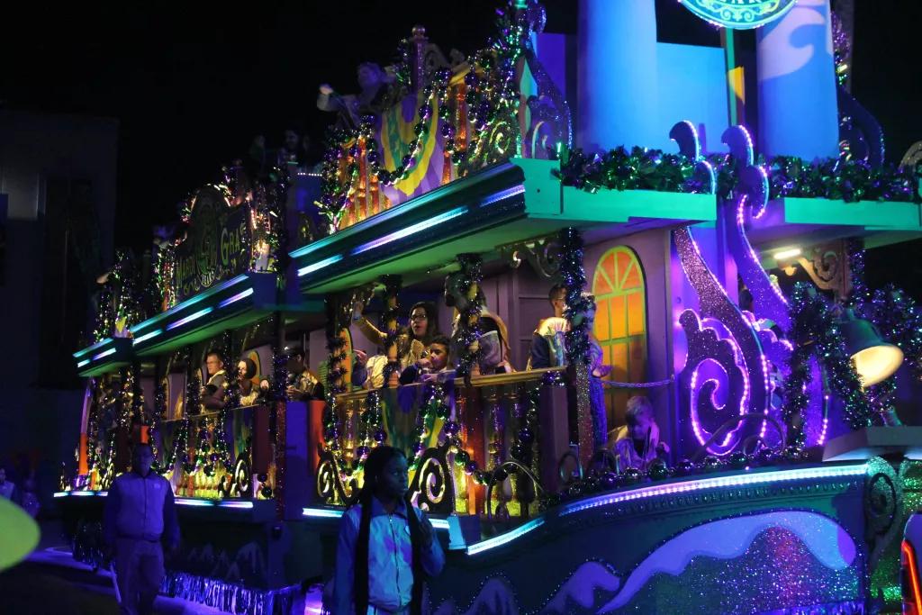 Universal Orlando Mardi Gras Parade A group of people on a parade float covered in large beads and glittery decorations