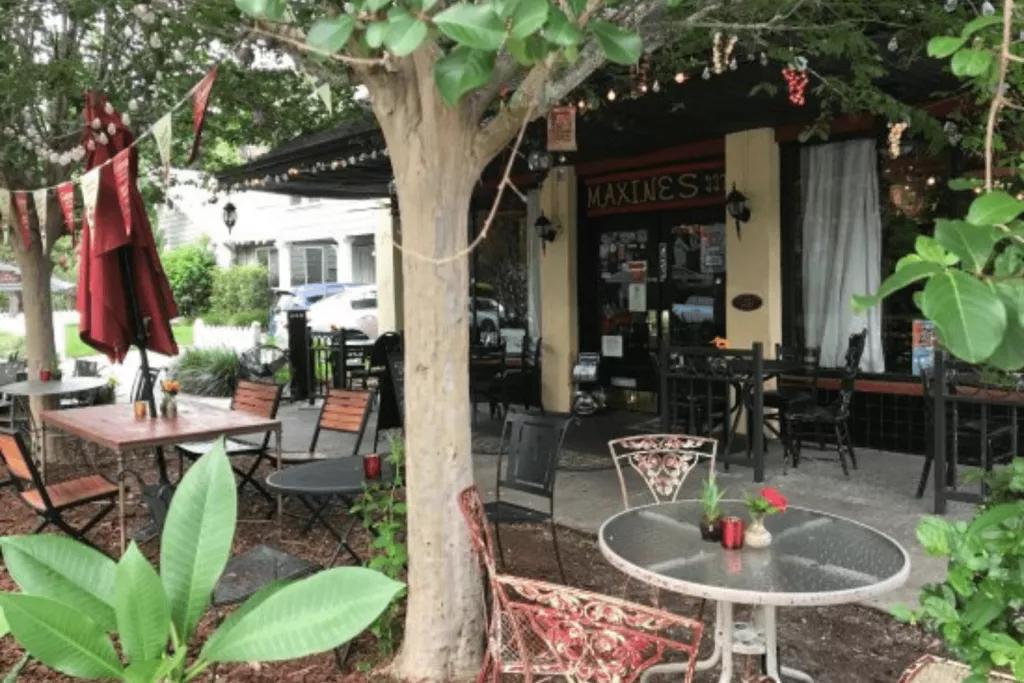 Maxine's On Shine The exterior of a restaurant with tables and mismatched chairs and a tree lit with fairy lights on the pavement