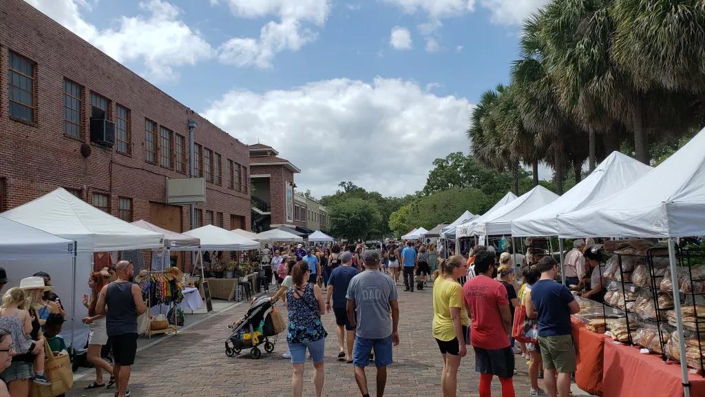 Winter Garden Farmers Market People walking through an outdoor farmers market lined with covered stalls selling food and clothes