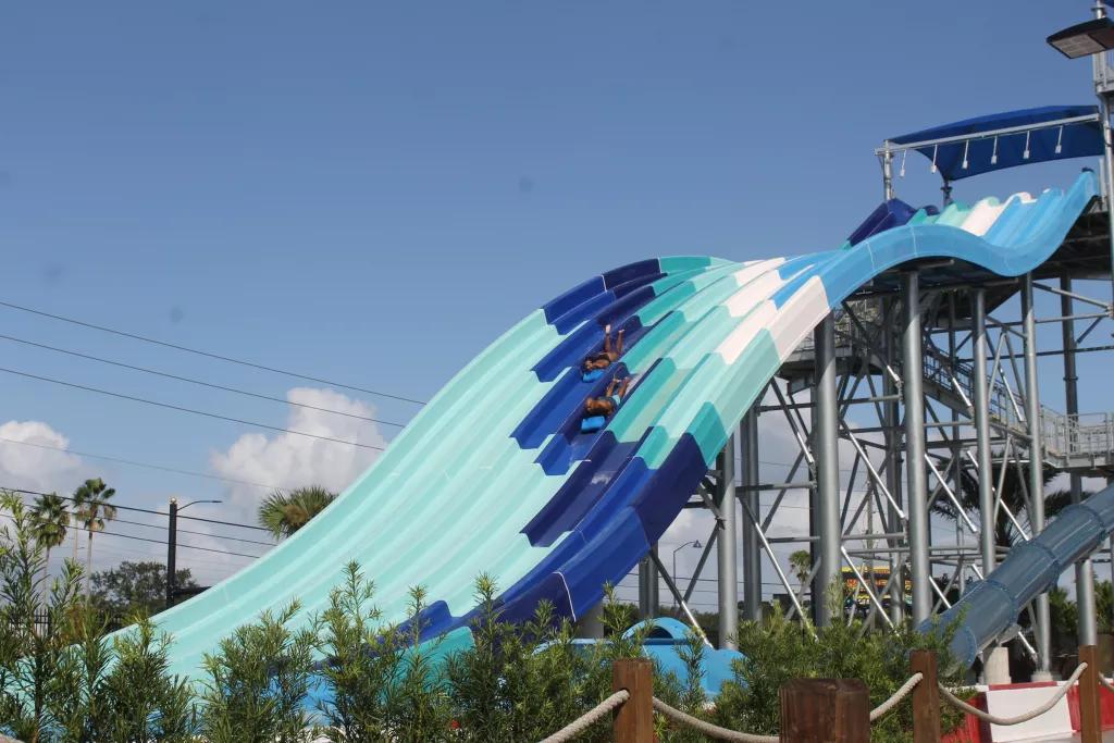 Reply Racers A blue striped water slide with two people sliding down head-first on mats