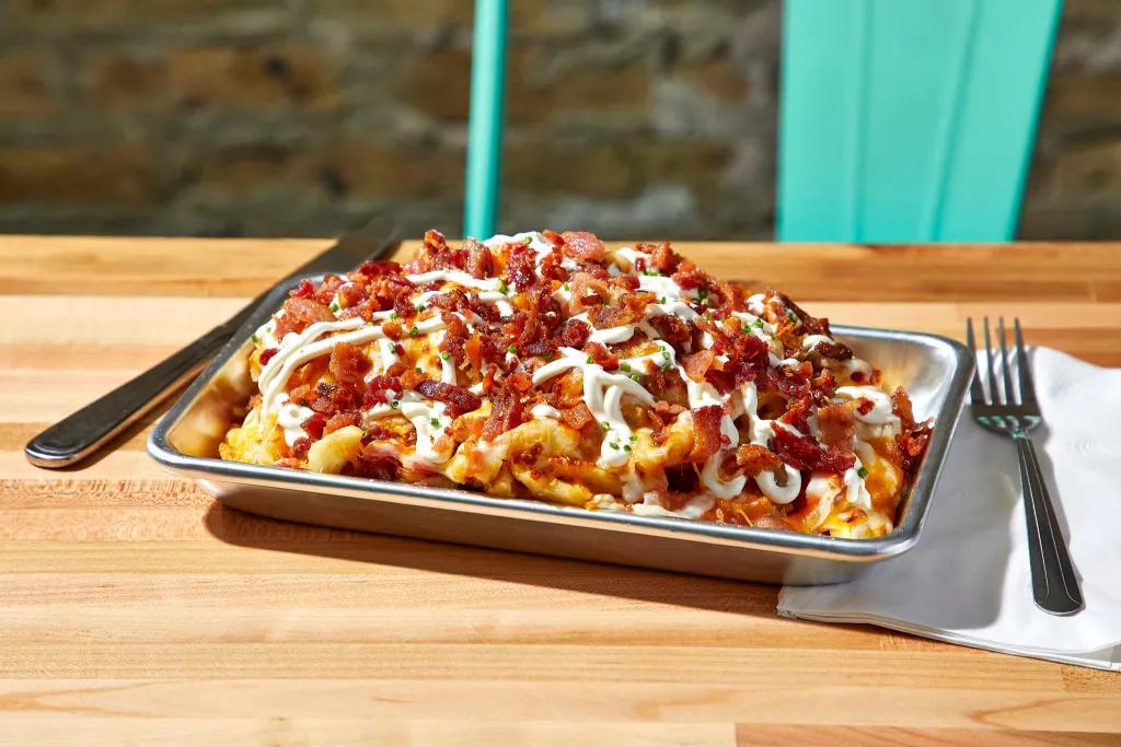 Loaded Fries at JoJos ShakeBar A metal tray piled high with waffle fries topped with bacon, cheese and sour cream