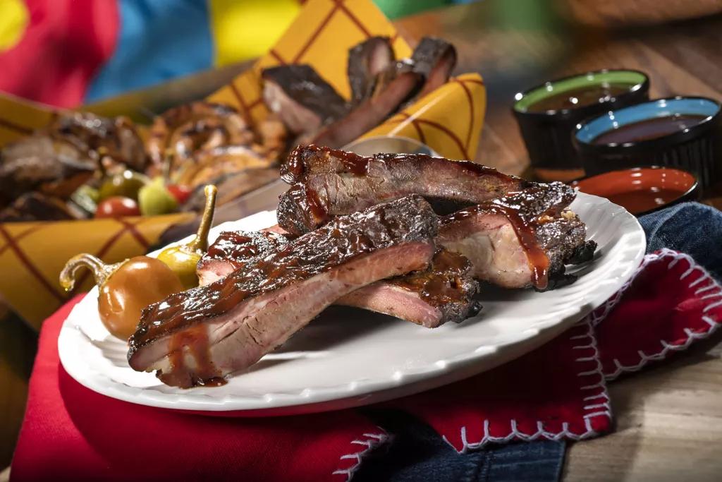 Evil Dr Smoked Ribs A plate full of barbecued ribs in front of a basket of other meats