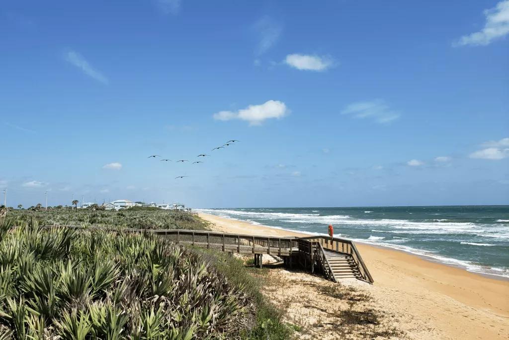 Flagler Beach A wooden walkway leading down to a sandy beach and blue ocean