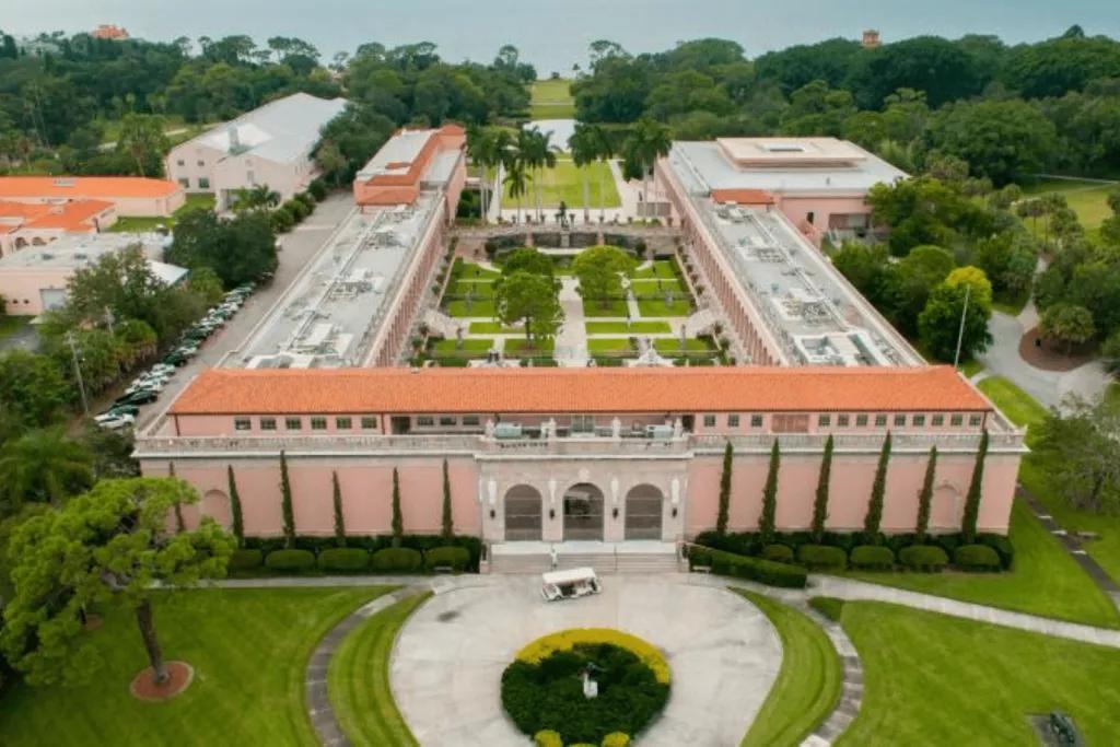 Ringling Art Museum An aerial view of a roman-style building surrounding a courtyard with the sea in the background