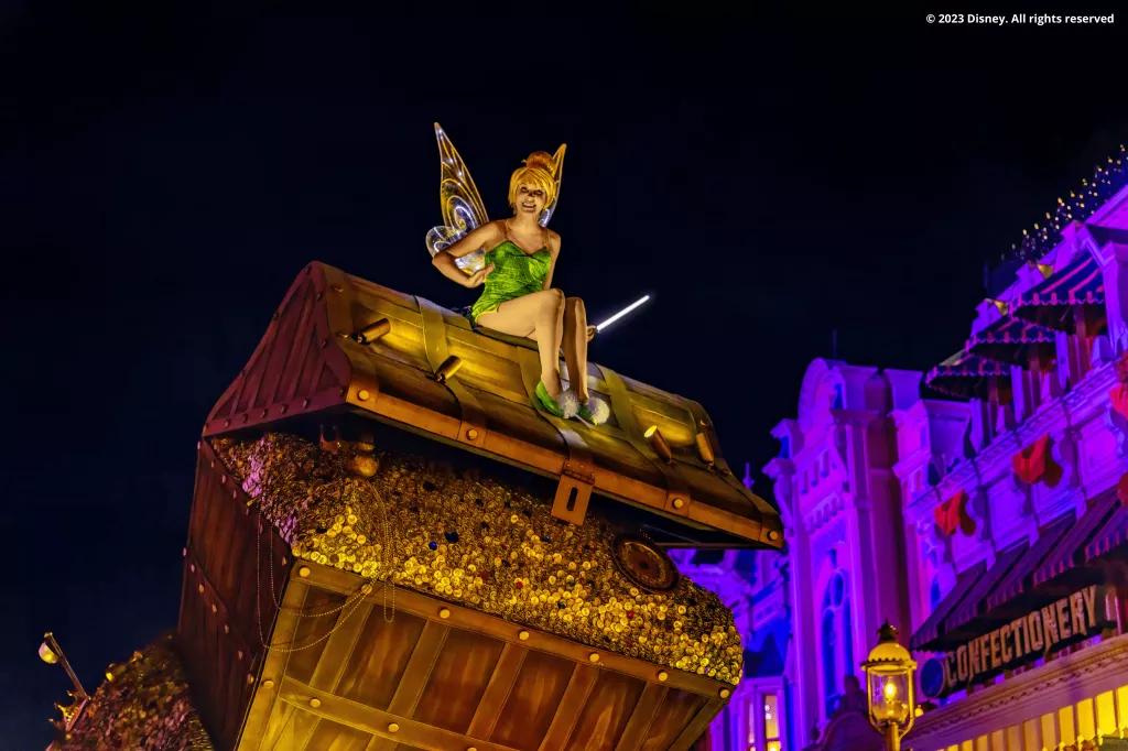 Mickey's Boo To You Parade Tinkerbell sat on top of a large chest full of treasure waving down at guests
