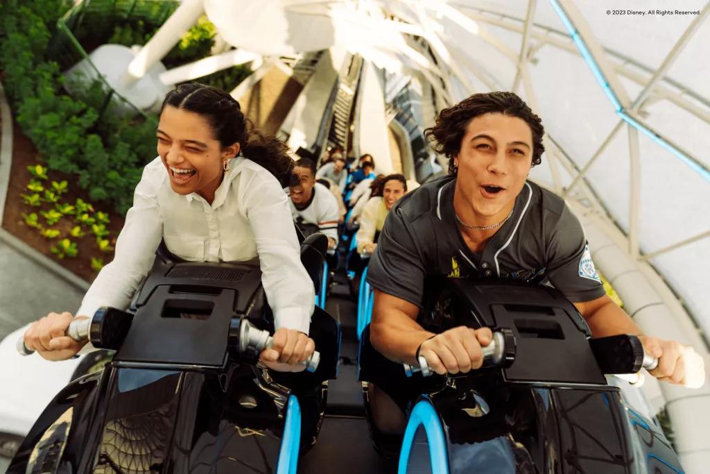 TRON Lightcycle / Run at Magic Kingdom Park A man and woman smiling while riding TRON at Disney World on ride vehicles shaped like motorbikes