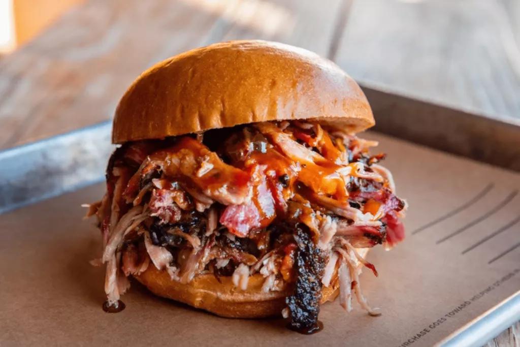 4 Rivers Smokehouse A brioche bun filled with pulled pork, coleslaw and barbecue sauce, served on a metal tray